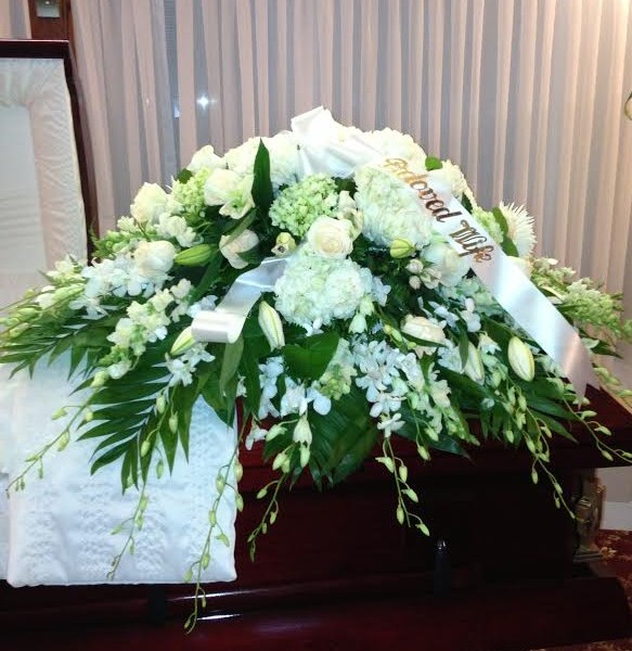 A casket with flowers on it in front of a window.