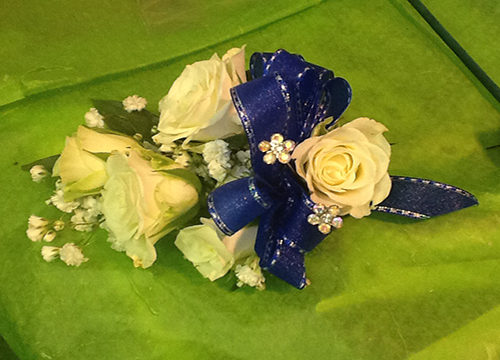 A blue and white corsage with flowers on green cloth.