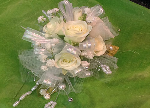 A bouquet of white roses with pearls on top.