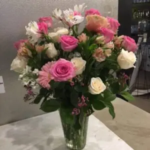 A vase filled with pink and white flowers on top of a table.