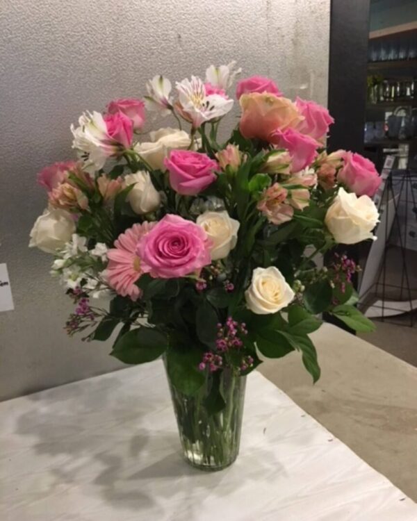 A vase filled with pink and white flowers on top of a table.