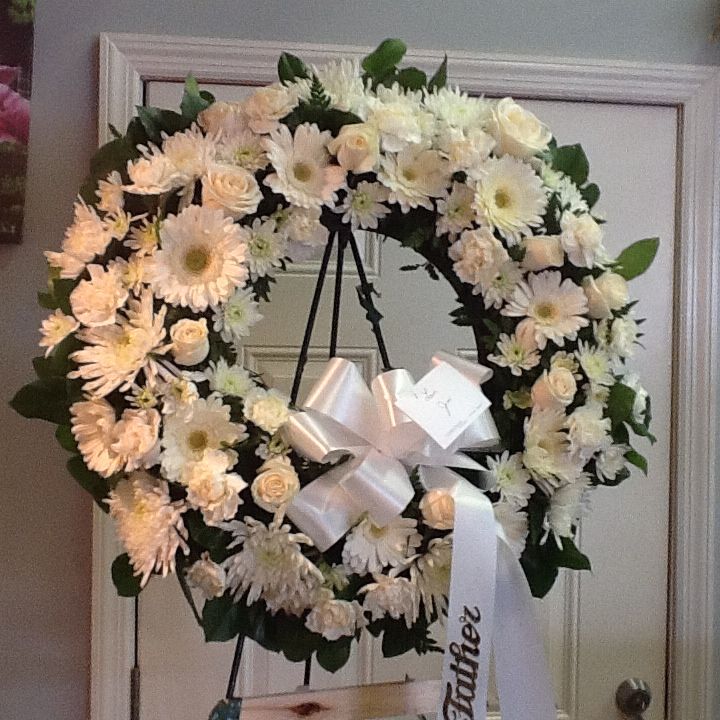 A wreath of white flowers on a stand.