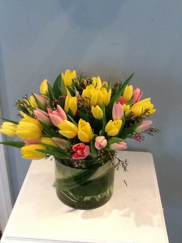 A vase filled with yellow and pink flowers.