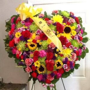 A heart shaped wreath of flowers with a banner.