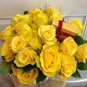 A bouquet of yellow roses with a gift box.