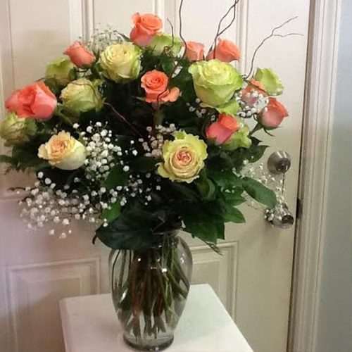 A vase of roses on the table in front of a door.