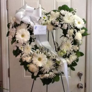 A heart shaped wreath of white flowers on display.